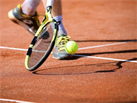 Ein Tennisspieler schlägt einen Ball mit seinem Schläger